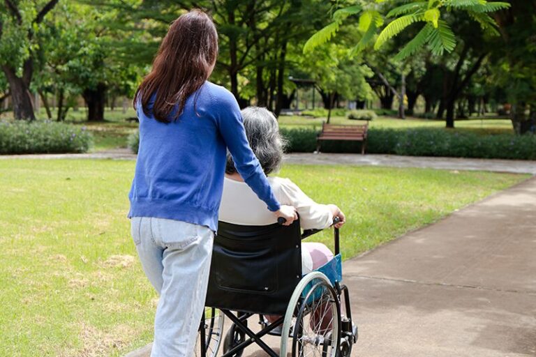 Une femme âgée bénéficiant de l'ASI en fauteuil roulant accompagnée de son aidante