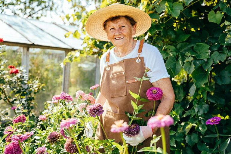 Activités seniors : une femme âgée qui s'occupe de ses plantes dans son jardin.