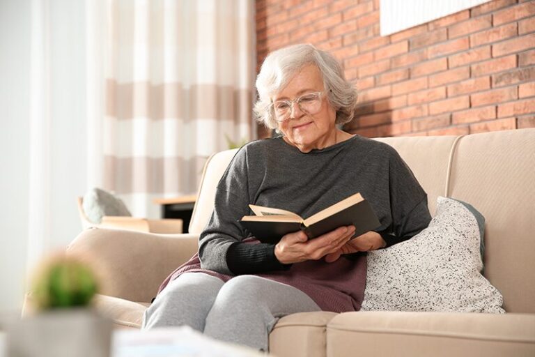 Une personne âgée atteinte de DMLA lisant un livre dans son salon