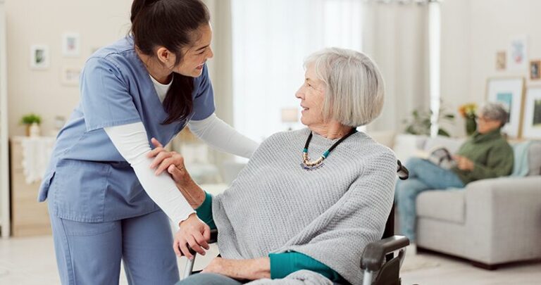 Une personne âgée dans son fauteuil qui est dans la section UVP d'un EHPAD avec une infirmière, dans une ambiance joviale.