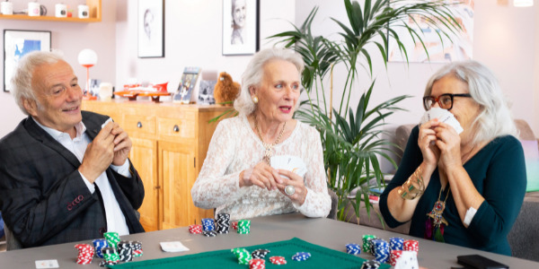 Trois personnes âgées dans un habitat partagé jouent aux cartes dans une ambiance conviviale